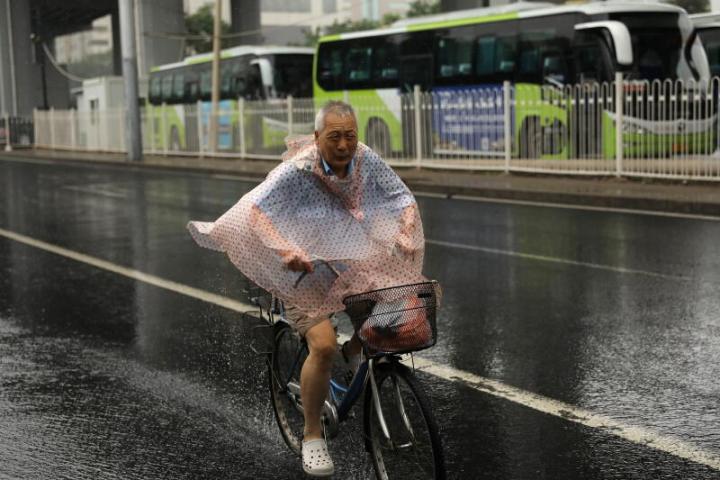 一名男子穿着雨衣在暴雨中骑行