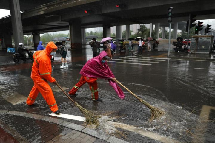 清洁工人们今早高峰时段清除道路积水