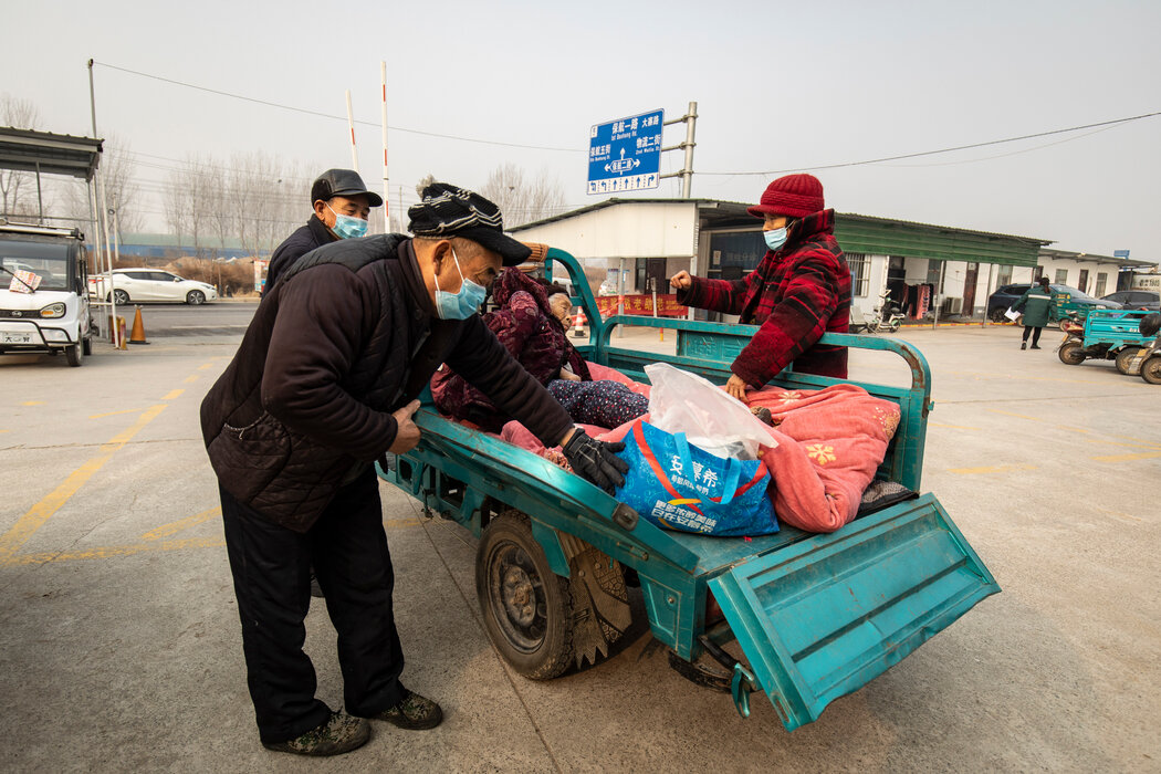 中国中部，一名女子被人抬上了一辆三轮摩托，他们刚从县医院出来。随着新冠病毒的广泛传播，资金不足的农村 ...